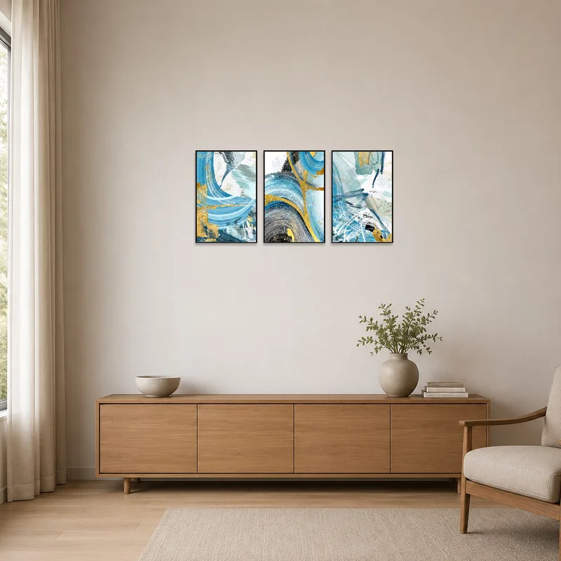 Gold-accented abstract triptych displayed in a minimalistic room with white walls and simple furnishings.
